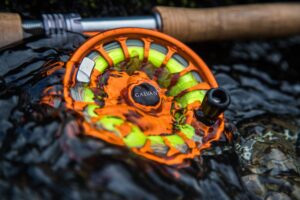 Orange fly fishing reel in water.